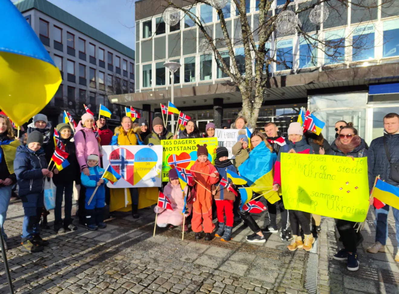 Folkemengde med ukrainske flagg og håndlagde plakater samlet på torget i Larvik under markeringen av ettårsdagen for invasjonen.