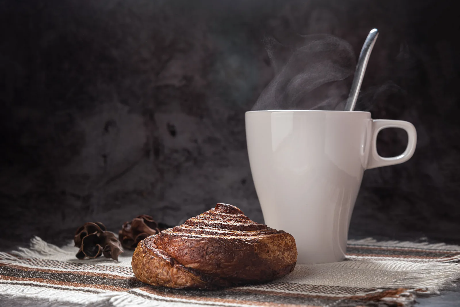 Kanelbolle og en dampende kaffekopp på et bord