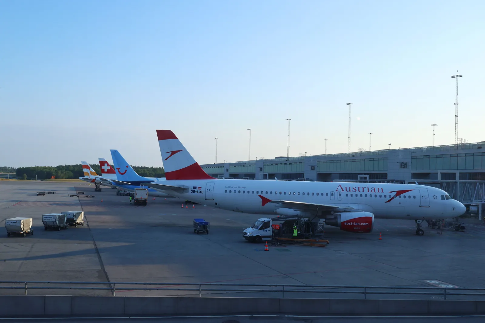 Tidlig fly fra Gardermoen: fly parkert ved terminalen på Oslo lufthavn i dagslys