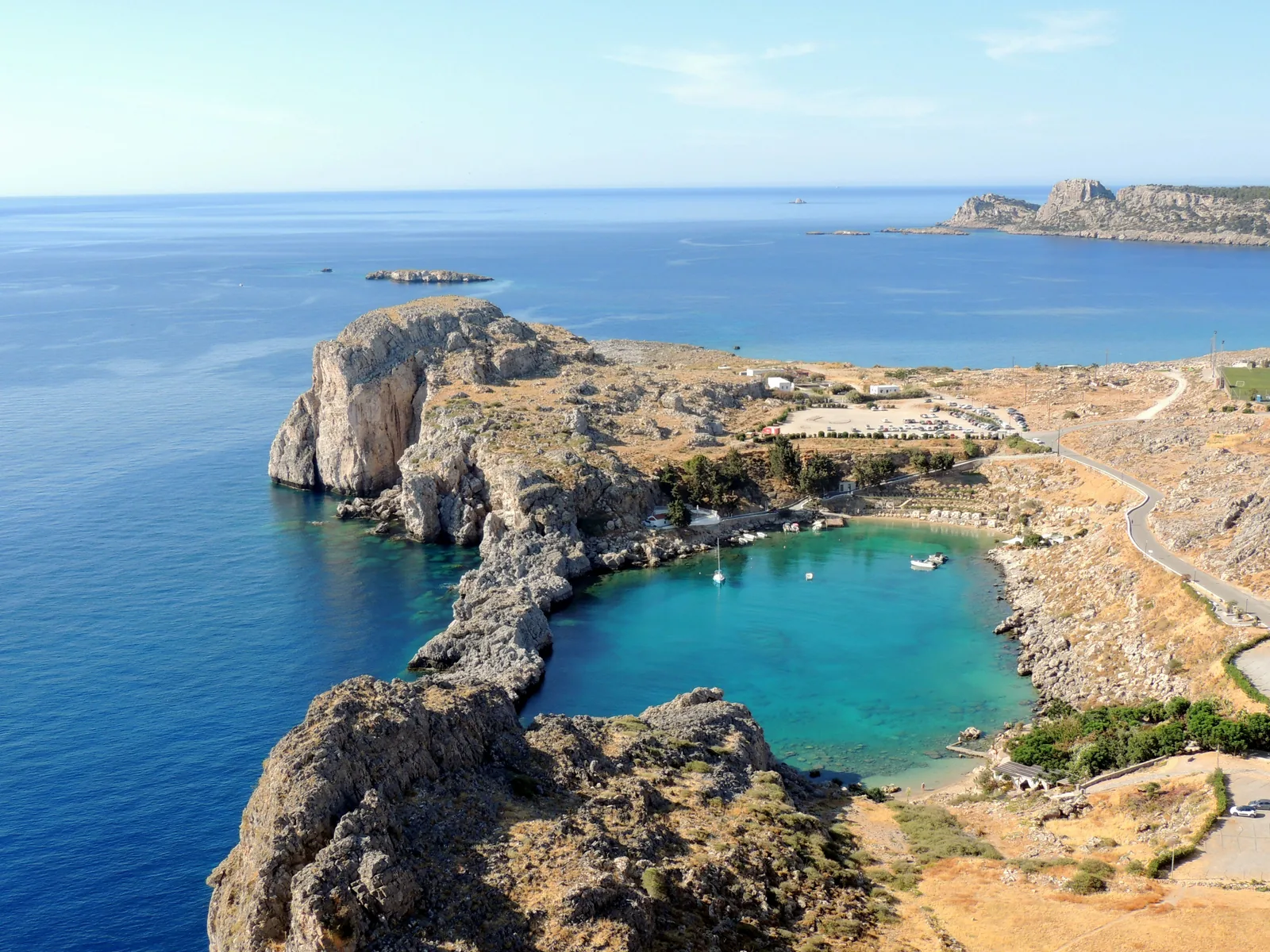 Turkis bukt med klipper og småbåter ved Lindos på Rhodos