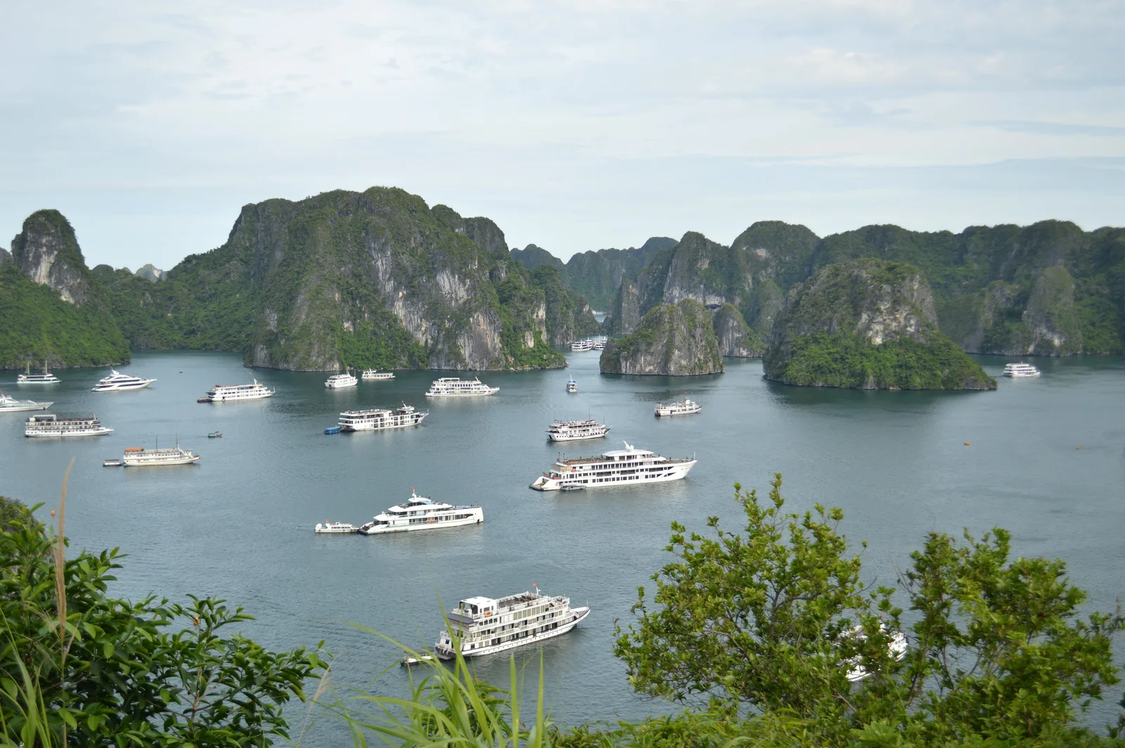 Cruisebåter for anker i Ha Long-bukten i Vietnam med kalksteinsøyer i horisonten