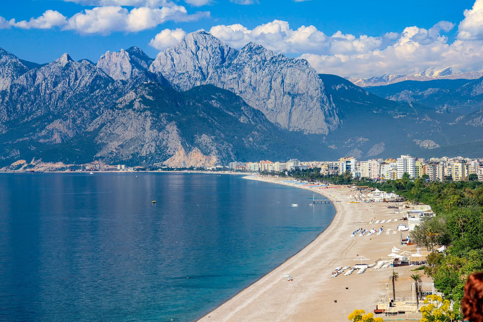 Lang sandstrand ved Antalya med blått hav og Taurusfjellene i bakgrunnen