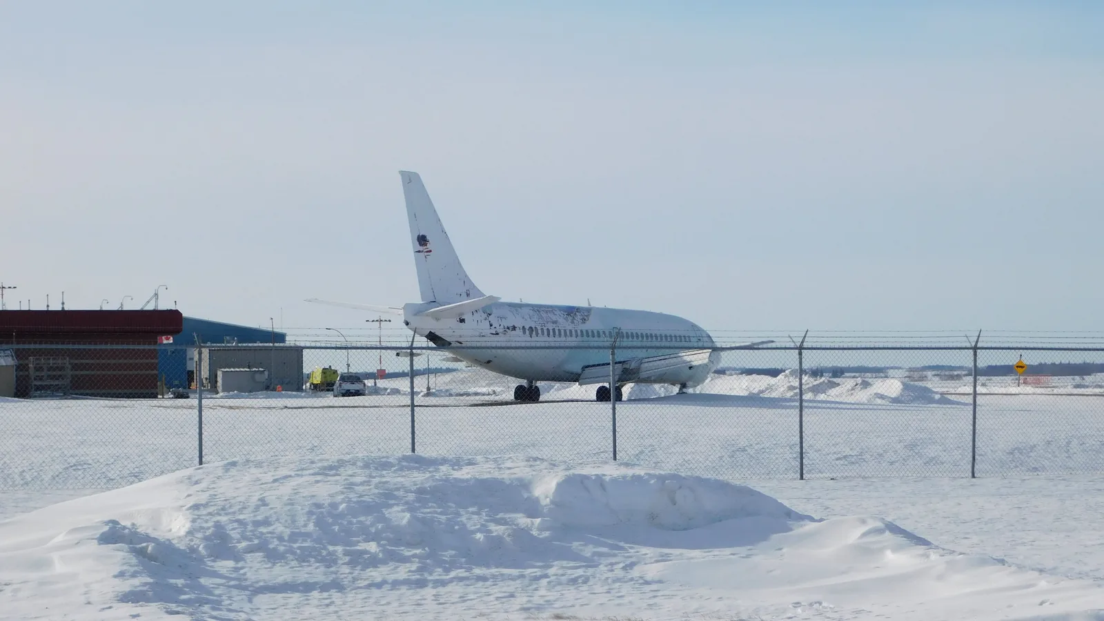 Passasjerfly parkert på en snødekt flyplass en lys vinterdag