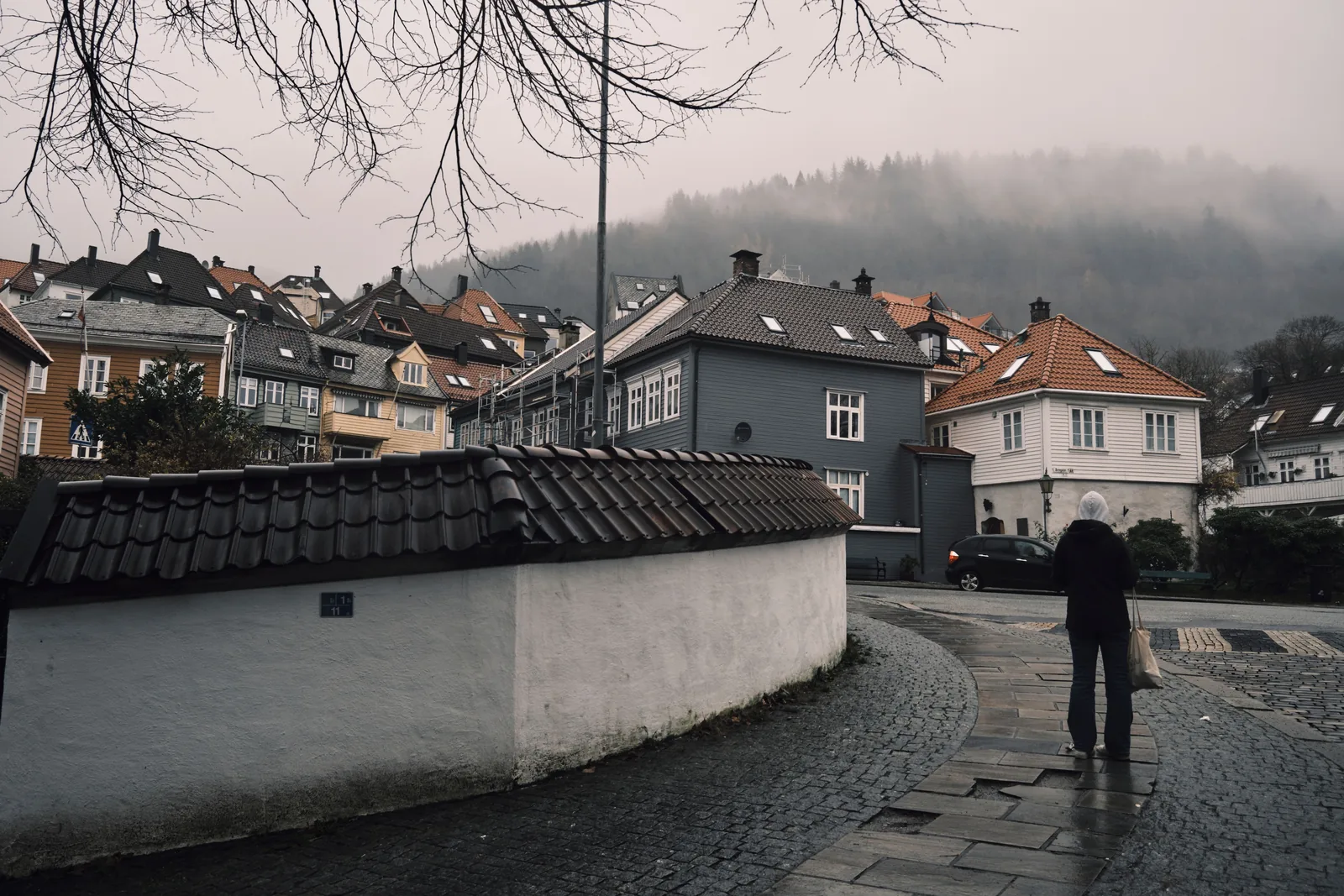 Rolig gate med hus og et murgjerde i tåke i Bergen