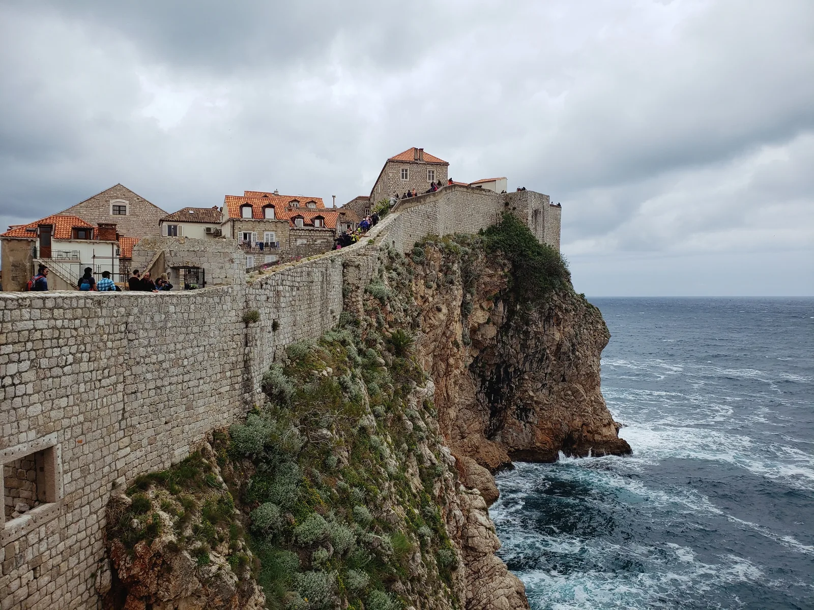 Bymuren i Dubrovnik på en klippe over det åpne Adriaterhavet med gamlebyens tak bak