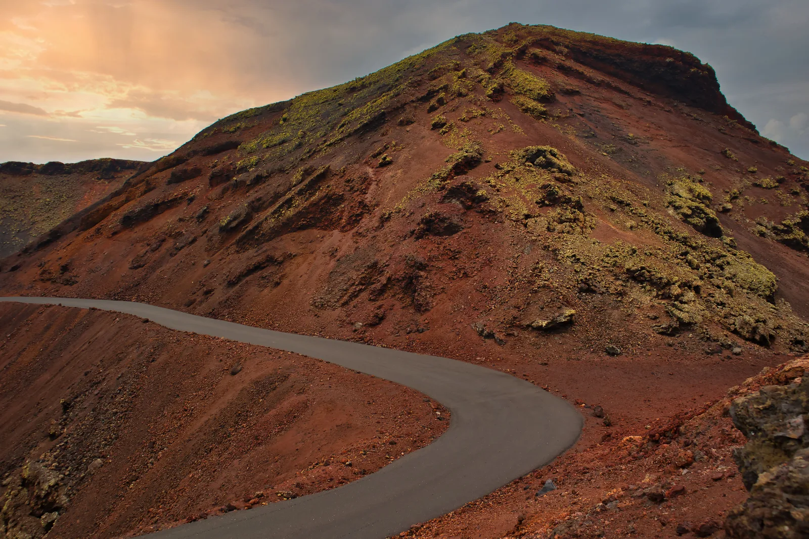 Buet vei som går gjennom rødt vulkanlandskap på Lanzarote
