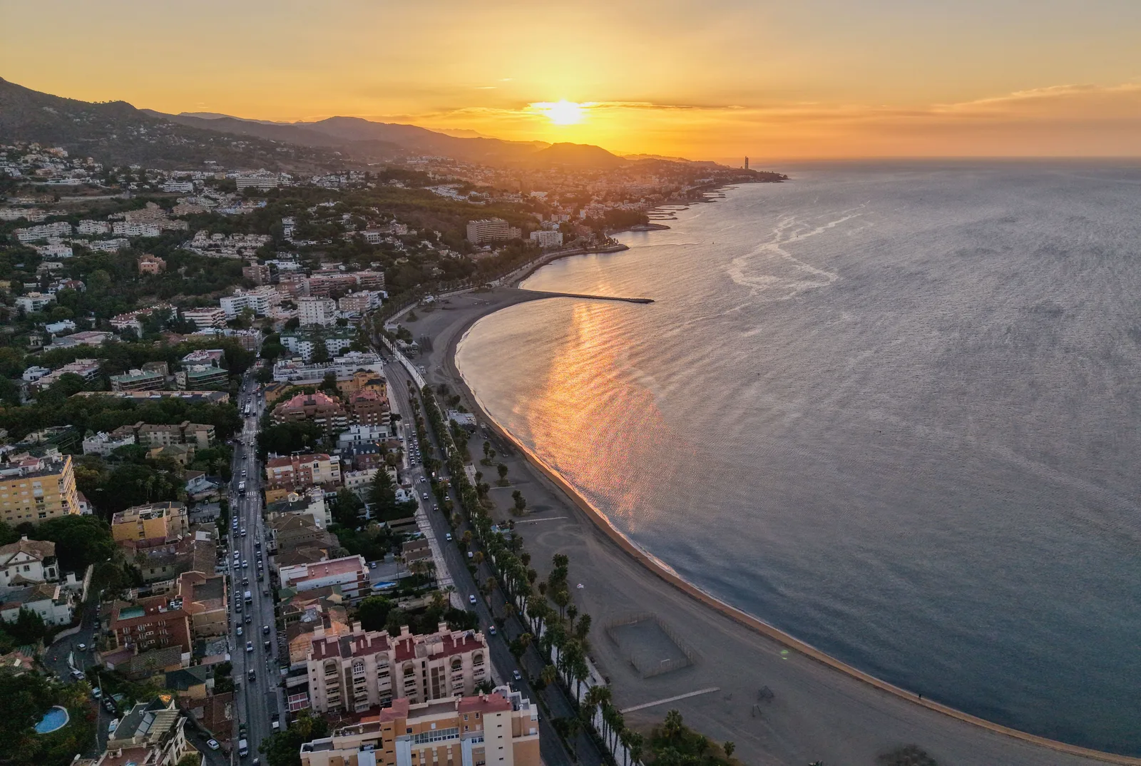 Flyfoto av stranden og byen langs Costa del Sol i solnedgang