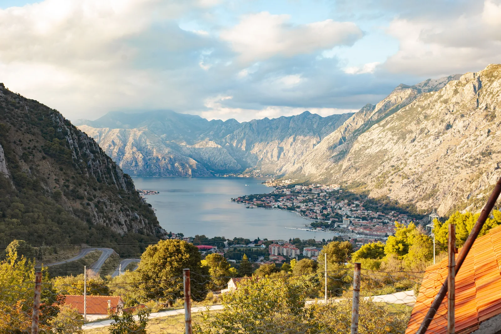 Utsikt over Kotorbukten fra fjellveien, med byen og fjellene i bakgrunnen og en vei som slynger seg i forgrunnen