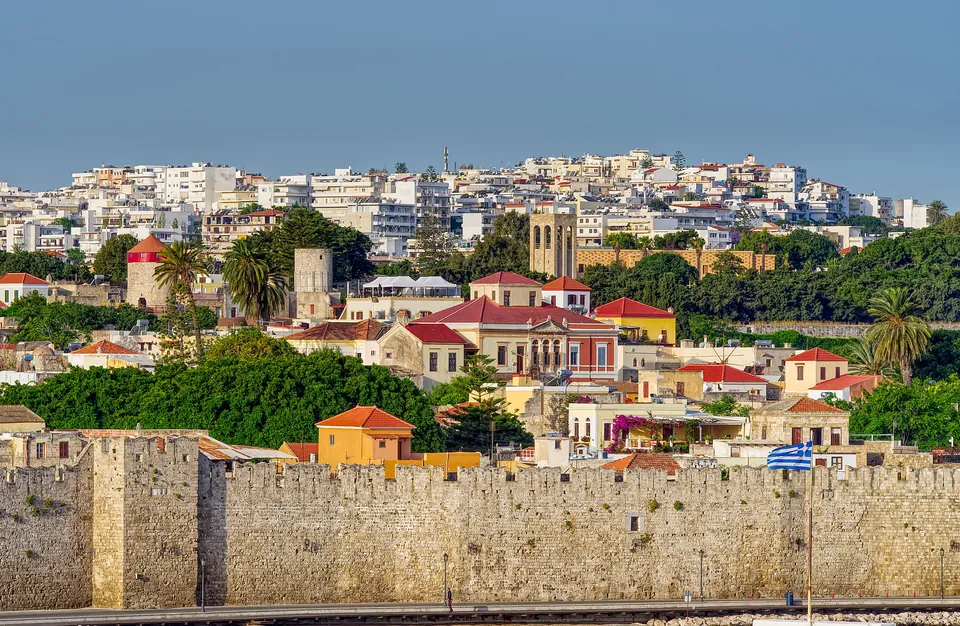 Bymuren og fargerike hus i Rhodos by under blå himmel