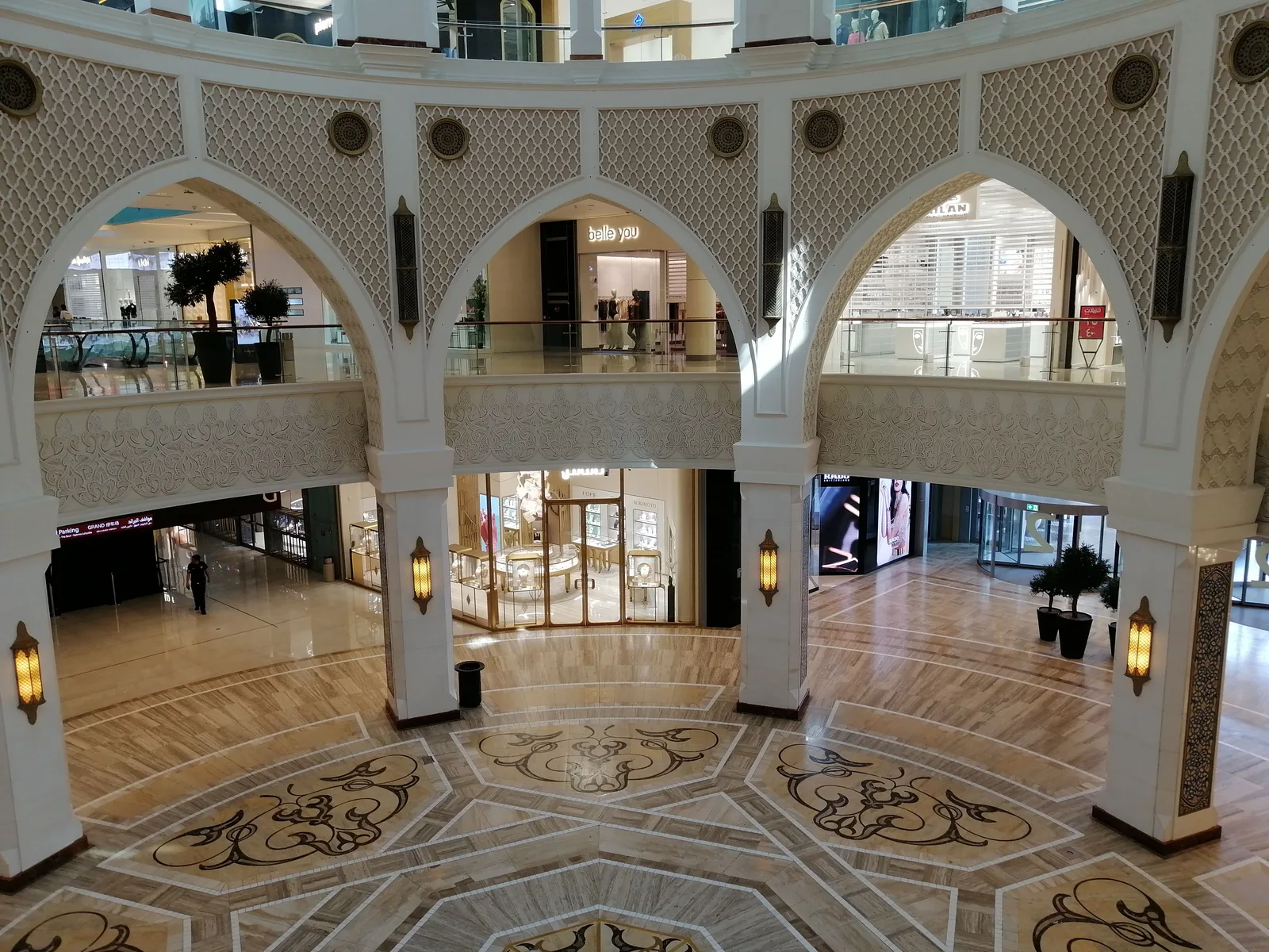 Kjøpesenter i Dubai med hvite buer, mosaikkgulv og flere etasjer med butikker